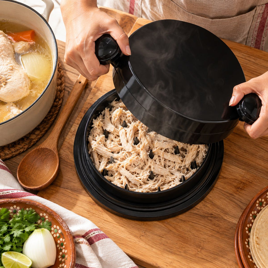 Manos levantando la tapa de TingaPro con pollo recién deshebrado